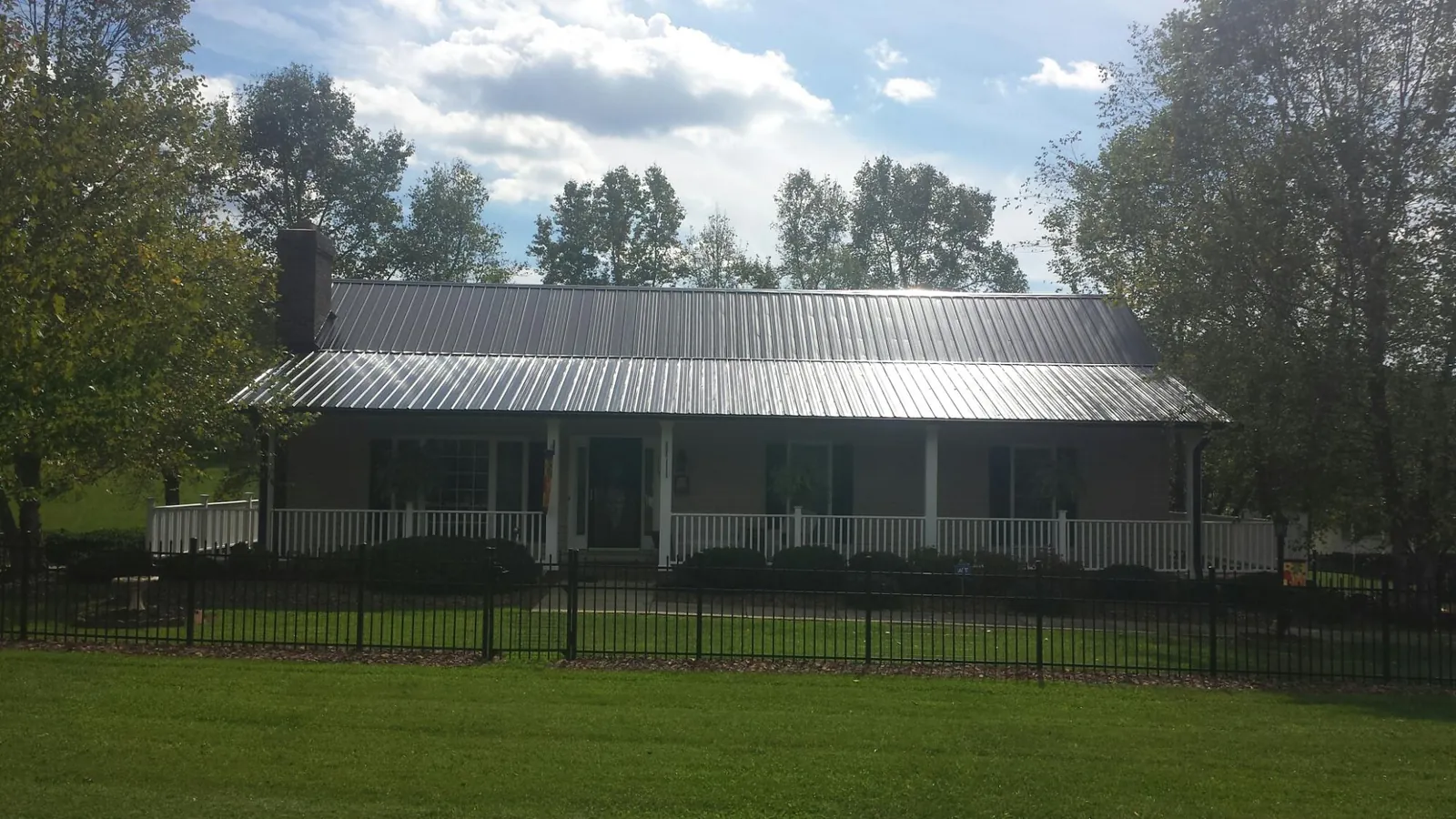 Gray metal roof on a brick ranch with a full width front porch — Gutter Guard Installation work by our crew in Rillton
