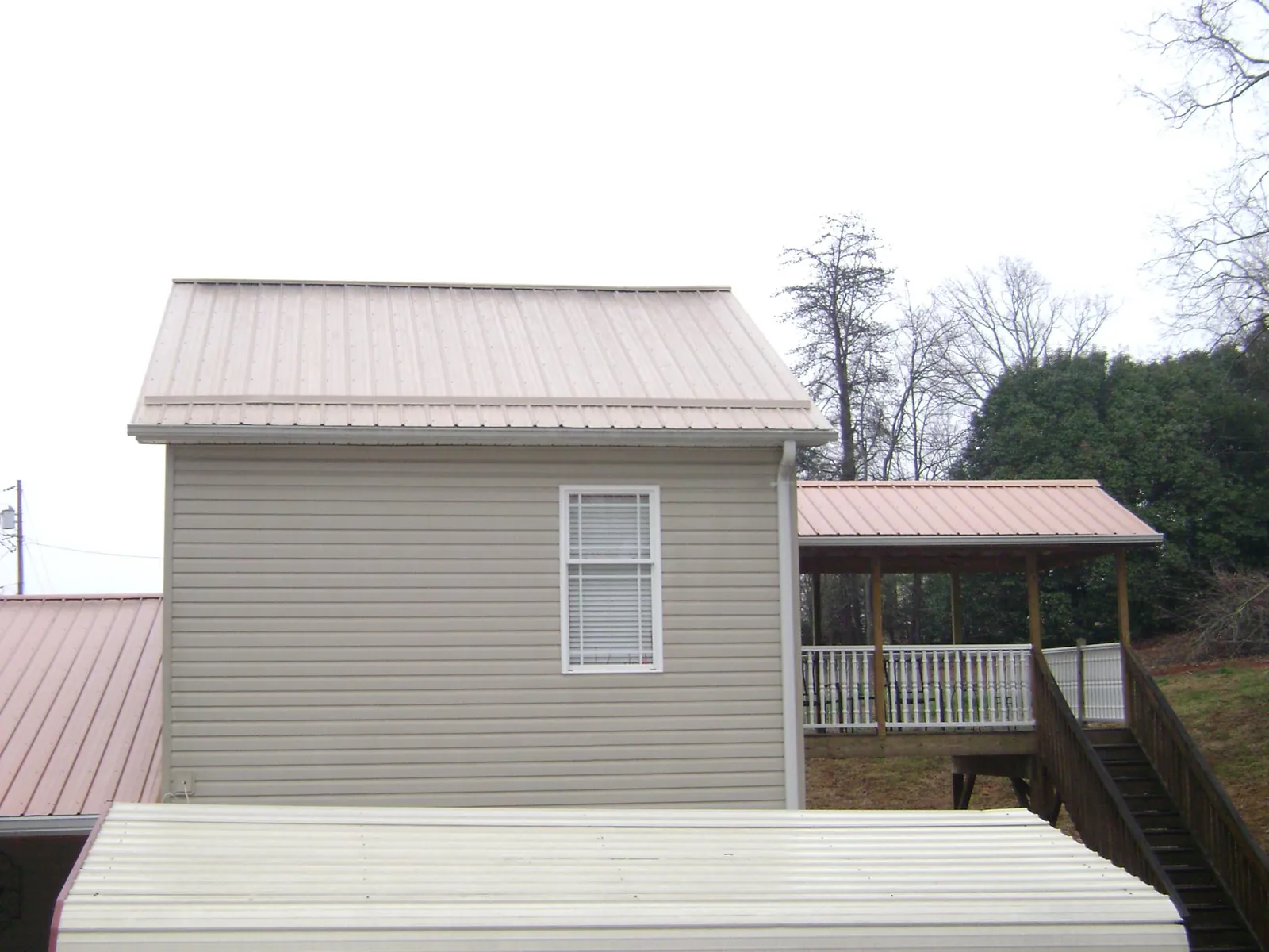 Tan metal roofs on a two story addition and attached porch, from a Roof Replacement job in Rillton